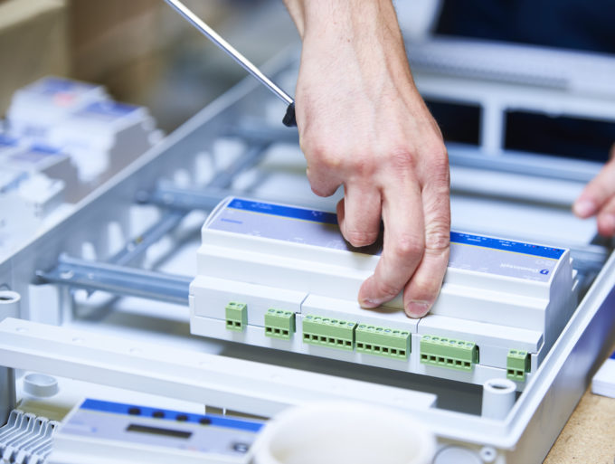 electrician-installer placing a DGQG02 Master module on a rail in an electrical cabinet